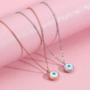 Titanium steel evil eye pendant necklaces in rose gold and silver on pink textured background