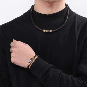 Macro detail of dark brown braided leather necklace and bracelet set with metallic beads