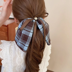 Close-up of a blue and brown plaid bow hair clip with ribbons on a woman's hair