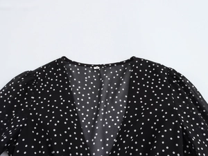 Detail of V-neckline with delicate stitching and white polka dots on black chiffon fabric