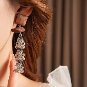 Detail of wooden square earrings with silver hollow tassel bells in bohemian style