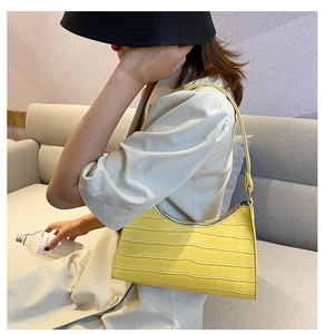 Fashionable yellow faux leather handbag with crocodile texture shown in a lifestyle setting