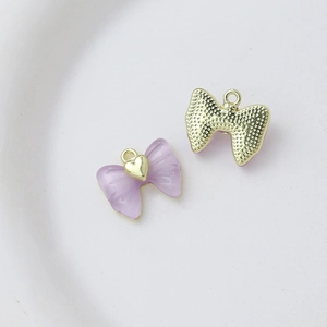 Detail of purple resin bow pendant with gold heart accent and textured metallic back