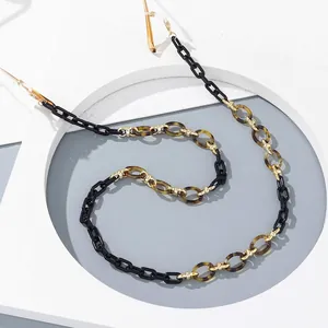 Detail of acrylic eyeglass chain with black and tortoiseshell links on white frame