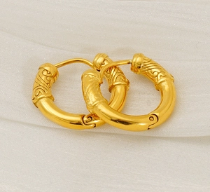 Macro shot of gold stainless steel huggie earrings featuring vintage scroll relief details