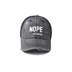 Detail of grey washed denim fabric with 'NOPE.' slogan and distressed mesh back