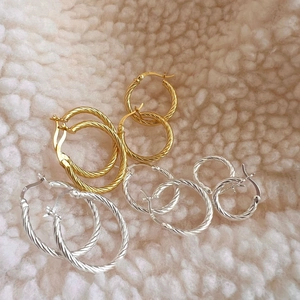 925 silver twist hoop earrings in gold and silver set on white fleece background
