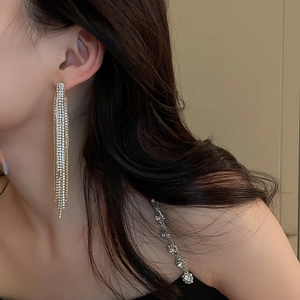 Detail of long emerald leaf tassel earrings with gold finish on model's side profile