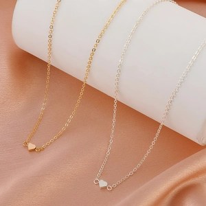 Elegant gold and silver heart pendant necklaces displayed on champagne silk fabric