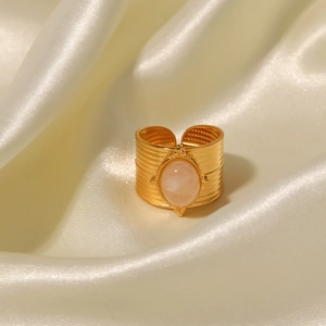 Detail of 18K gold stainless steel wide ring with pink gemstone on beige silk