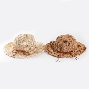 Détail de chapeaux en paille tressée avec bords ondulés et fines brides en cuir nouées