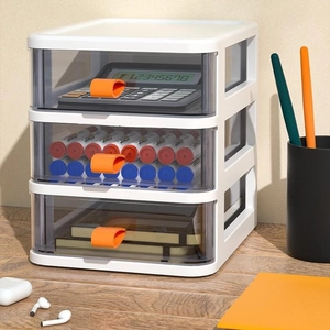 Three-tier white storage drawer with transparent bins and orange handles on wooden desk