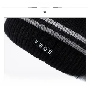 Detail shot of black knitted beanie with grey stripes and stitched FBQE logo label