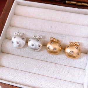 Detail of 18K gold plated apple earrings with matte brushed finish and star zircons