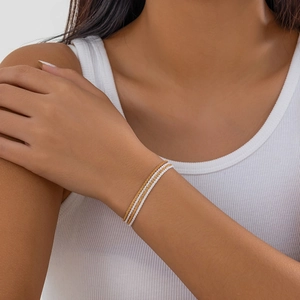 Detail of three-layer braided chain bracelet in gold and silver mix on model's wrist