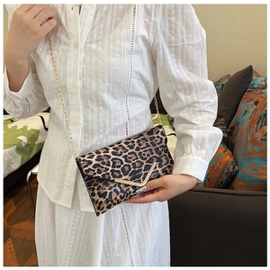 Close-up of leopard print clutch with golden V-shaped buckle and fine chain strap