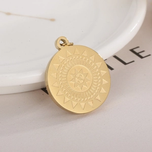 Macro shot of a gold geometric sun totem pendant on a white ceramic plate surface