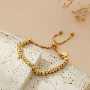 Golden stainless steel beaded bracelet with heart pendant on natural stone base
