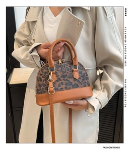 Close-up of leopard print panel on a brown PU leather dome bag held by a model