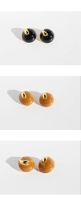 Detailed close-up of brown and black resin dome stud earrings with golden metal accents