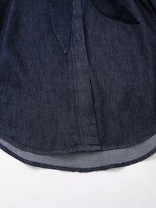 Gros plan d'une chemise en jean bleu foncé montrant l'ourlet incurvé et les détails