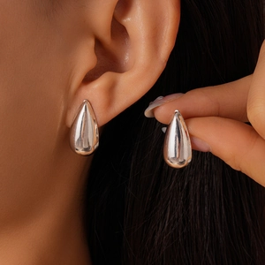 Gros plan de boucles d'oreilles clous goutte d'eau en argent poli portées à l'oreille