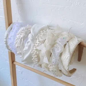Elegant assortment of white pearl and bow headbands for women on a wooden display