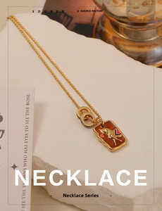 Close-up of golden beaded necklace with vintage red horse enamel pendant on a white stone