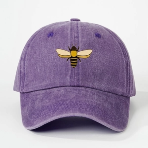 Close-up of embroidered bee on washed purple cotton baseball cap with fabric texture