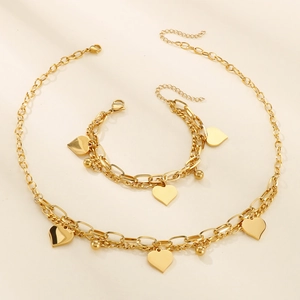 Detail of gold double-layer chain jewelry set with heart charms and small beads
