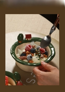Detailed view of handmade ceramic bowl with miniature 3D tree and house ornaments