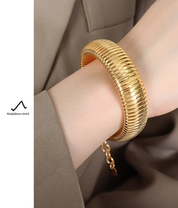 Detailed view of wide 18K gold plated stainless steel bracelet with striped texture on wrist