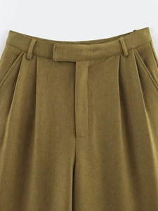Detailed macro view of olive green high-waisted trousers showing pleated front and belt loops