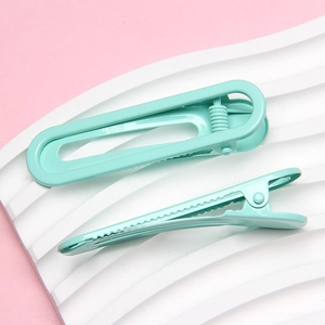 Close-up of mint green matte U-shaped metal hair clips on white decorative plate