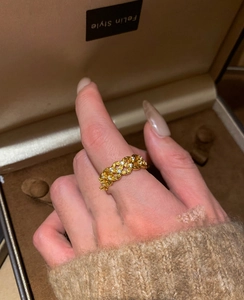 Close-up of gold-plated hollow-out ring with sparkling cubic zirconia on a finger