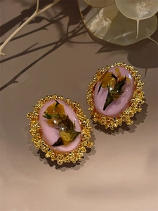 Close-up of vintage amber earrings with pink dried flowers and 18K matte gold textured edges