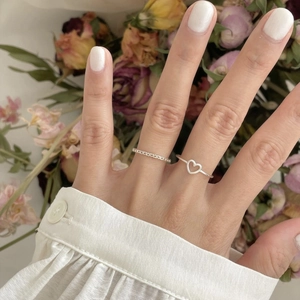 Close-up of a 925 sterling silver hollow heart ring and textured band on fingers