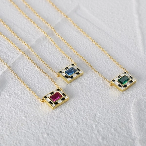 Macro detail of checkered enamel necklaces with red, blue and green gemstones