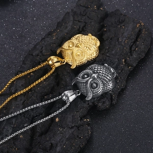 Detailed view of gold and silver owl pendants with intricate feather texture on black rock