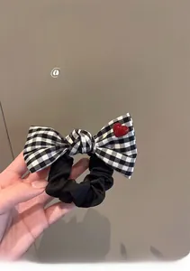 Detail of checkered bow hair scrunchie with a red heart button accent and black fabric