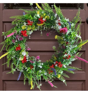 Dettaglio di ghirlanda di fiori selvatici artificiali su una porta di legno bruno