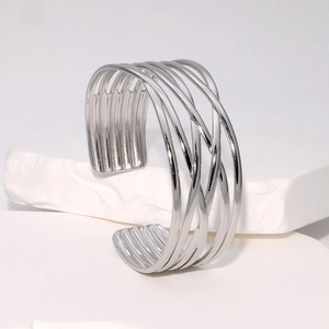 Bracelet jonc ouvert en acier inoxydable tressé argenté sur un support en plâtre blanc