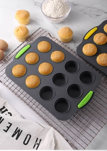 Close-up of a 12-cup grey silicone muffin pan with green handles on a cooling rack