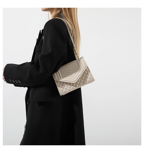 Detailed view of beige quilted leather bag with V-shaped stitching and gold chain