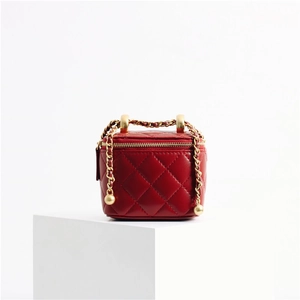 Detailed close-up of a red quilted leather mini bag featuring gold chain and metal ball clasp