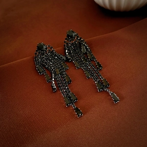 Détails de boucles d'oreilles frangées en zircon noir sur fond en tissu texturé marron