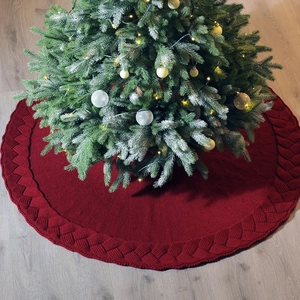 48 inch red knitted Christmas tree skirt with thick cable weave texture on wood floor