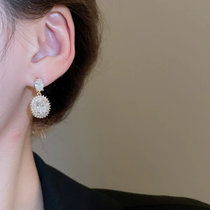 Detailed view of square zircon drop earrings with gold finish on a model