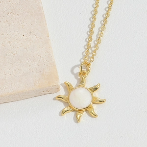 Close-up of golden sun pendant with white shell inlay on a natural stone surface