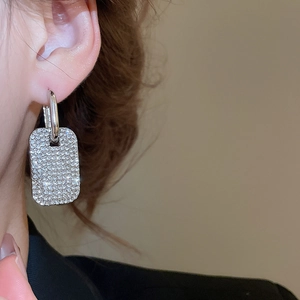 Dettaglio di orecchini quadrati in argento con cristalli micro-pave su modella